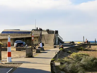 a group of people sitting on a sidewalk near the beach at 6 person holiday home in Thisted-By Traum in Torsted