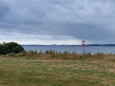 a sign in a field next to a large body of water at 8 person holiday home in Roslev-By Traum in Roslev