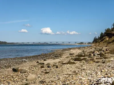 a rocky beach with a bridge in the background at 8 person holiday home in Roslev-By Traum in Roslev