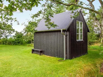 a black shed with a bench in a field at 8 person holiday home in Roslev-By Traum in Roslev