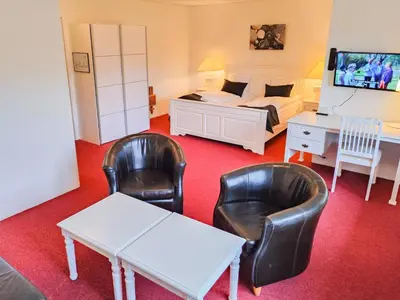 a bedroom with a bed and two chairs and a desk at Rønnes Hotel in Fjerritslev