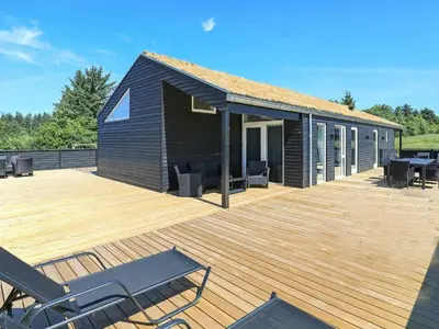 a house with a wooden deck with chairs on it at 8 person holiday home in Saltum-By Traum in Saltum
