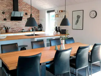 a dining room with a wooden table and black chairs at 8 person holiday home in Saltum-By Traum in Saltum