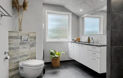 a bathroom with a toilet and a sink and two windows at Three-Bedroom Holiday Home In Vestervig in Vestervig