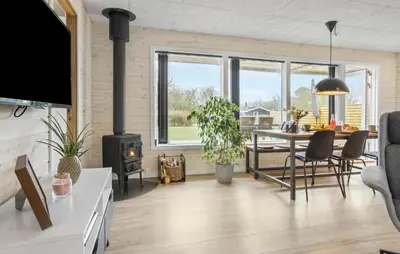 a living room with a dining table and a stove at Three-Bedroom Holiday Home In Vestervig in Vestervig