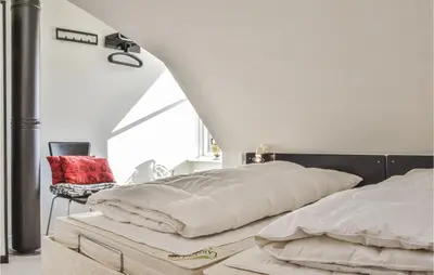 a bedroom with two beds and a chair in it at 2 Bedroom Lovely Apartment In Lemvig in Lemvig