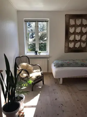 a room with a bed and a chair and a window at Tranum Lys og Glas in Brovst