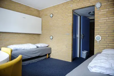 a room with two beds and a brick wall at Idrætscenter Jammerbugt in Fjerritslev