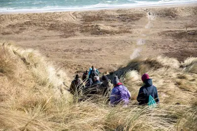 a group of people are walking down a beach at Idrætscenter Jammerbugt in Fjerritslev