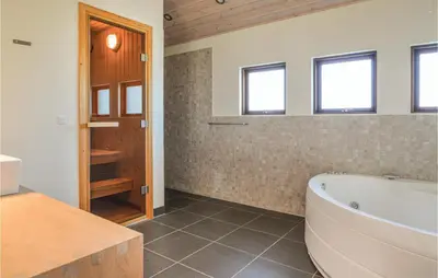 a bathroom with a tub and a sink and windows at Five-Bedroom Holiday Home In Lokken in Løkken