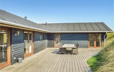 a patio with a table and chairs on a house at Five-Bedroom Holiday Home In Lokken in Løkken