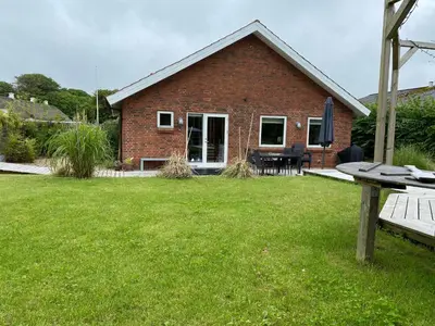 a brick house with a table and a bench in the yard at Hyggeligt byhus ved glasværkstedet på Nordmors in Sejerslev