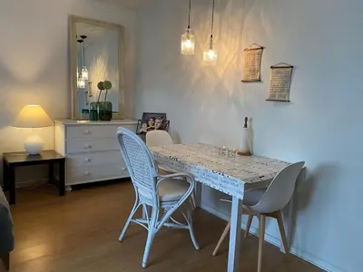 a dining room with a table with chairs and a dresser at Motel Hune Apartments in Blokhus