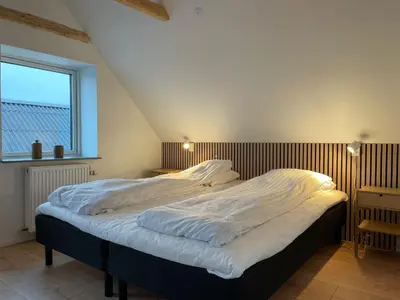 a bedroom with a large bed with white sheets at Motel Hune Apartments in Blokhus