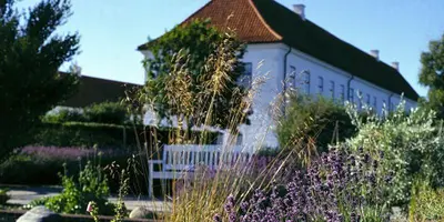 a white building with a bench in a garden at Vitskøl Kloster in Ranum