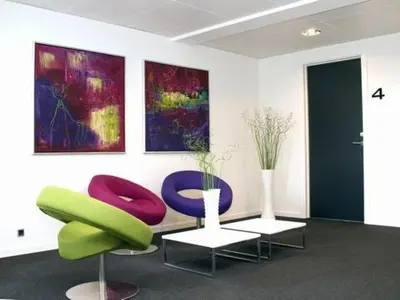 a room with two chairs and a table and paintings at Seaside Hotel Thyborøn in Thyborøn