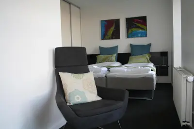 a room with two beds and a chair in front of a bed at Seaside Hotel Thyborøn in Thyborøn