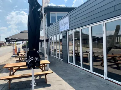 a umbrella sitting on a bench outside of a restaurant at Thyborøn Hotel in Thyborøn