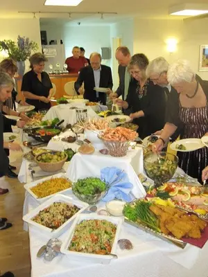 a group of people standing around a table full of food at Hotel Højgaarden in Slettestrand