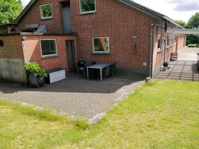 a brick building with a patio with a table at Bændal in Bækmarksbro