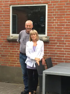 a man and a woman standing in front of a brick building at Bændal in Bækmarksbro