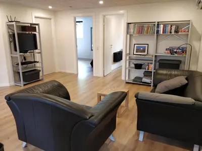 a living room with two leather chairs and a television at Bændal in Bækmarksbro