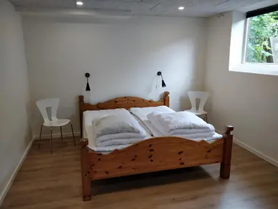 a bedroom with a wooden bed with two chairs and a window at Bændal in Bækmarksbro