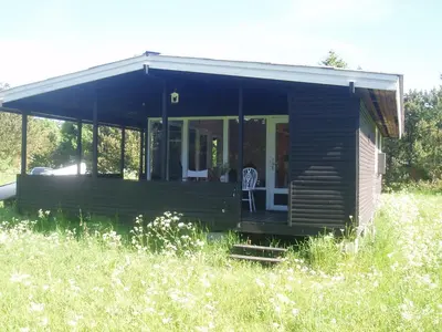 a wooden cabin in a field of tall grass at Summer cottage in Nøreng