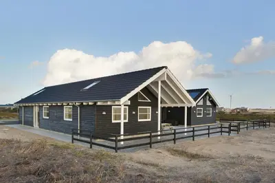 a house with a black roof on a beach at Luksus-poolhus L21 in Harboør