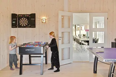 a woman and a child playing a game on a table at Luksus-poolhus L21 in Harboør