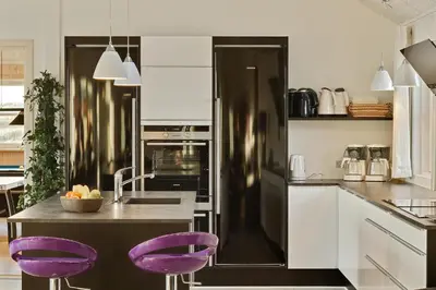 a kitchen with purple chairs and a refrigerator at Luksus-poolhus L21 in Harboør