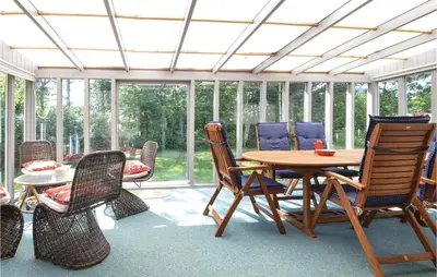 a conservatory with a wooden table and chairs at Three-Bedroom Holiday Home In Hjerm in Hjerm
