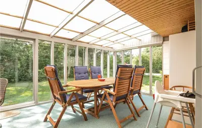 a conservatory with a wooden table and chairs at Three-Bedroom Holiday Home In Hjerm in Hjerm