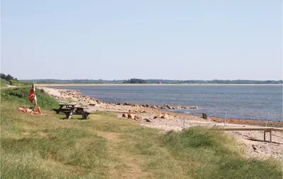 a bench on a beach next to a body of water at 9 Bedroom Beautiful Home In Spøttrup in Spottrup