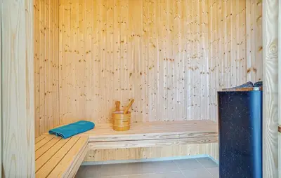 a wooden sauna with a blue pillow on a wooden bench at 9 Bedroom Beautiful Home In Spøttrup in Spottrup