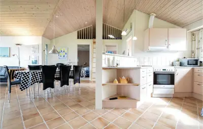 a kitchen and dining room with white cabinets and black chairs at Three-Bedroom Holiday Home In Vinderup in Vinderup