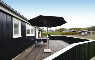 a patio with a table and an umbrella on a deck at Three-Bedroom Holiday Home In Vinderup in Vinderup