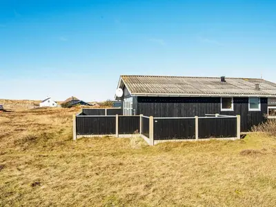 a black building in a field with a fence at Cozy Beach House Retreat - By Traum Ferienwohnungen in Harboør