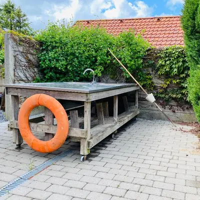 a wooden sink with an orange ring next to a hedge at Stor lys lejlighed på Nordmors in Sejerslev