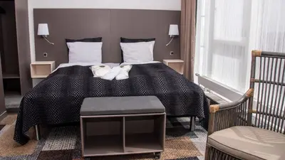 a bedroom with a bed with a black blanket and a chair at Hotel Skivehus in Skive