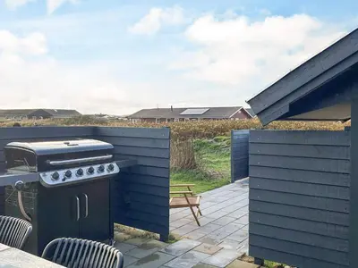 a grill on a patio with a table and chairs at 18 person holiday home in Harboøre in Harboør