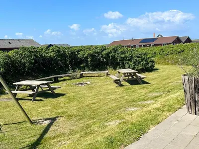 two picnic tables in the grass in a field at 18 person holiday home in Harboøre in Harboør