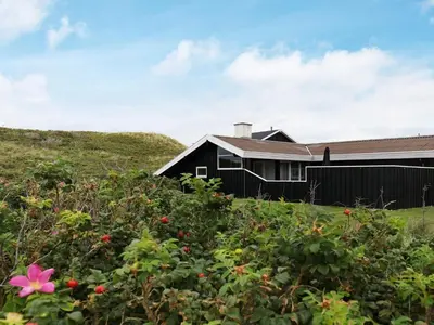 a house with a pink flower in the bushes at Seaside Serenity in Blokhus-By Traum in Blokhus