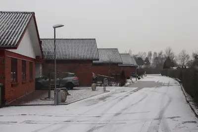 a snow covered street with houses and a car parked on the road at Holstebro Townside House in Holstebro