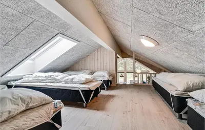 a attic room with three beds and a window at Nice Home In Spøttrup With Sauna in Spottrup