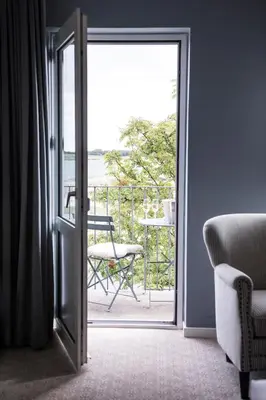 a room with a door open to a balcony with a chair at Tambohus Kro & Badehotel in Hvidbjerg