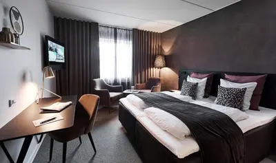 a hotel room with a large bed and a desk at Struer Grand Hotel in Struer