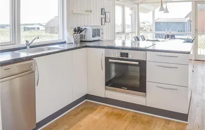 a kitchen with white cabinets and a sink and a stove at Three-Bedroom Holiday Home In Harboore in Harboør
