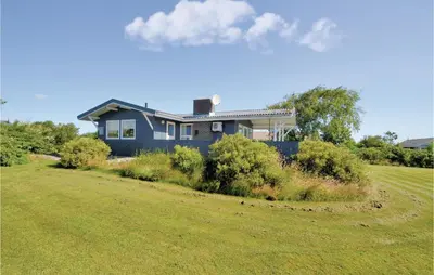 a blue house in a field with a yard at Three-Bedroom Holiday Home In Hurup Thy in Doverodde