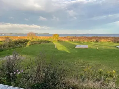 a large green field with a view of the ocean at 6 person holiday home in Farsø-By Traum in Farsø